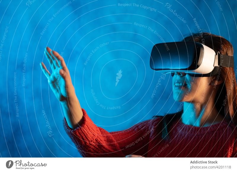 Woman in VR goggles exploring virtual reality woman vr headset touch experience explore illuminate projector technology innovation gadget entertain digital