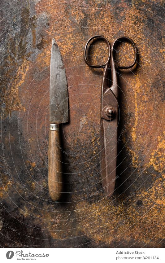 Old metal scissors and knife on table rust old shabby weathered surface aged instrument tool grunge steel dark equipment metallic worn out desk iron manual