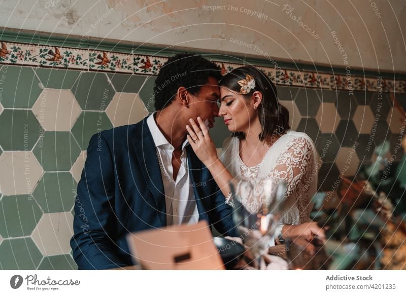 Multiethnic newlywed couple at table with decoration on wedding day marriage relationship festive celebrate restaurant portrait flower multiracial eyes closed