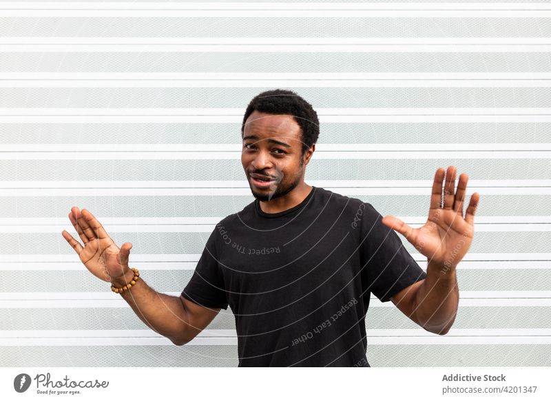 Cheerful black male standing near striped wall man cheerful sincere friendship happy portrait content glad smile candid positive friendly toothy smile enjoy