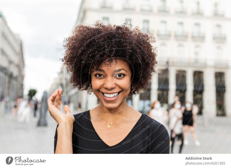 Smiling black woman on urban pavement in daytime cheerful candid friendly charming afro hairstyle street city portrait african american happy smile ethnic