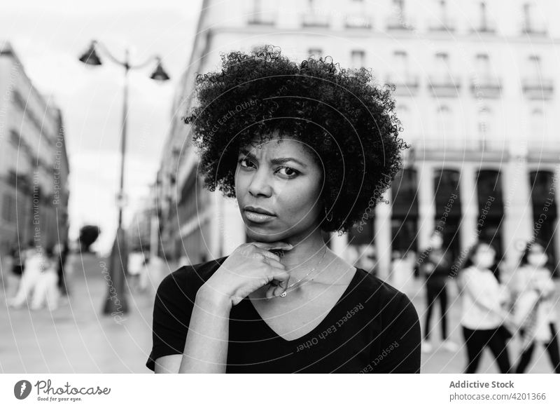 Pensive black woman on urban pavement in daytime afro hairstyle street city portrait african american ethnic square town casual cloth female summer curly hair