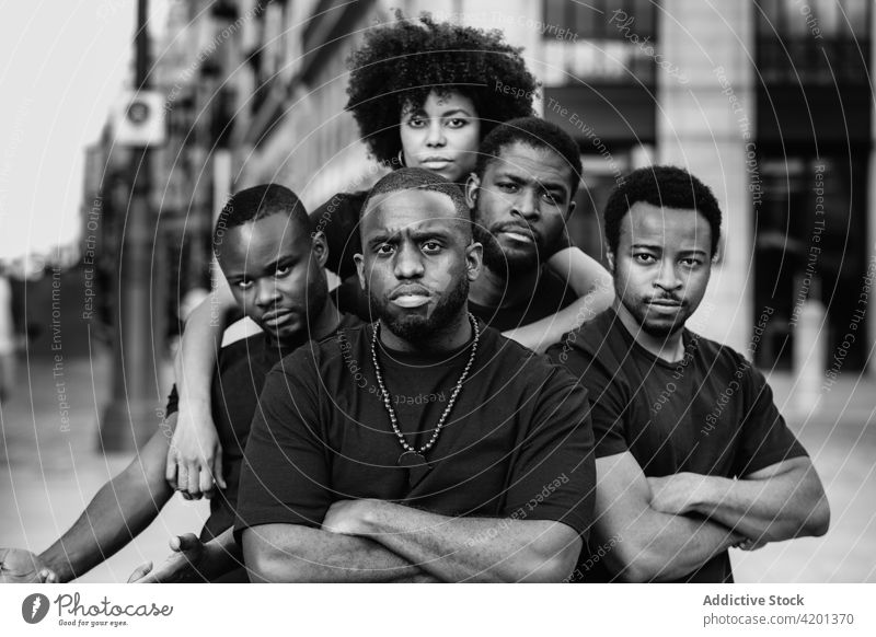 Confident black friends embracing on city street embrace self assured arms crossed friendship confident serious team portrait town woman men masculine