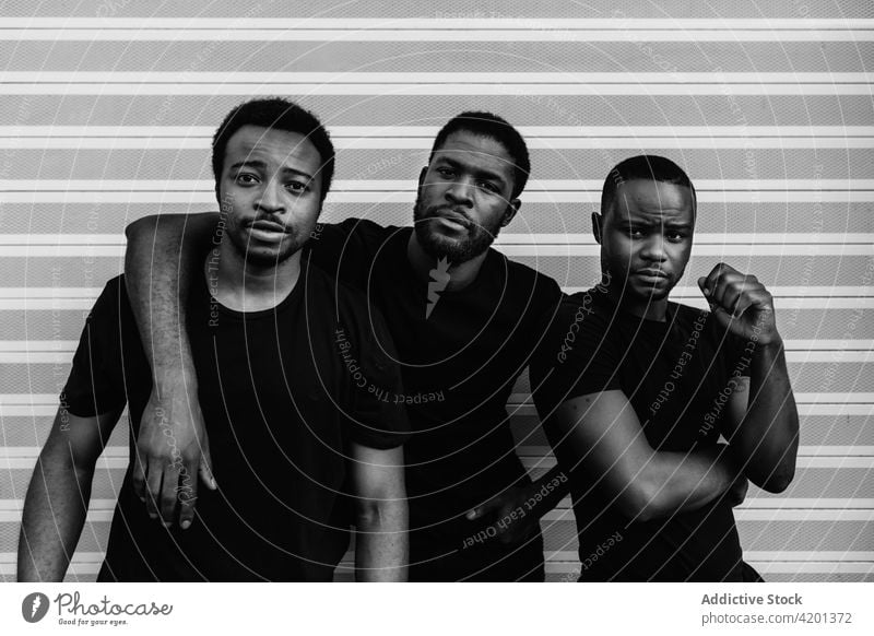 Black male friends embracing near striped wall serious friendship blm movement portrait justice equality black lives matter embrace racism social democracy sjw
