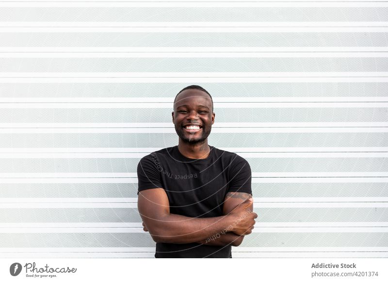 Cheerful black male standing near striped wall man cheerful sincere friendship happy portrait content glad smile candid positive friendly toothy smile enjoy