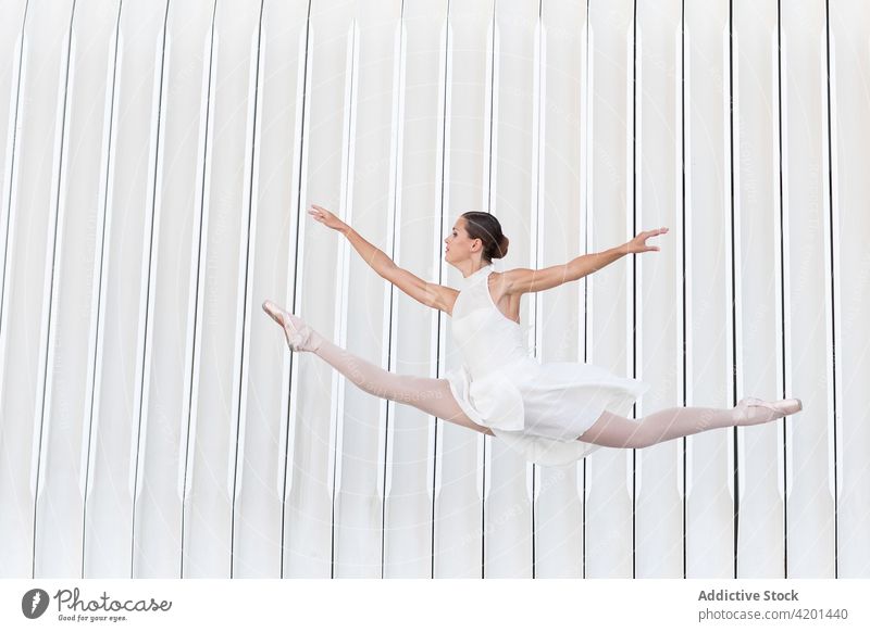 Professional ballerina jumping in air on street dance classic art choreography leg raised grace exercise woman arm raised dancer ballet feminine flexible
