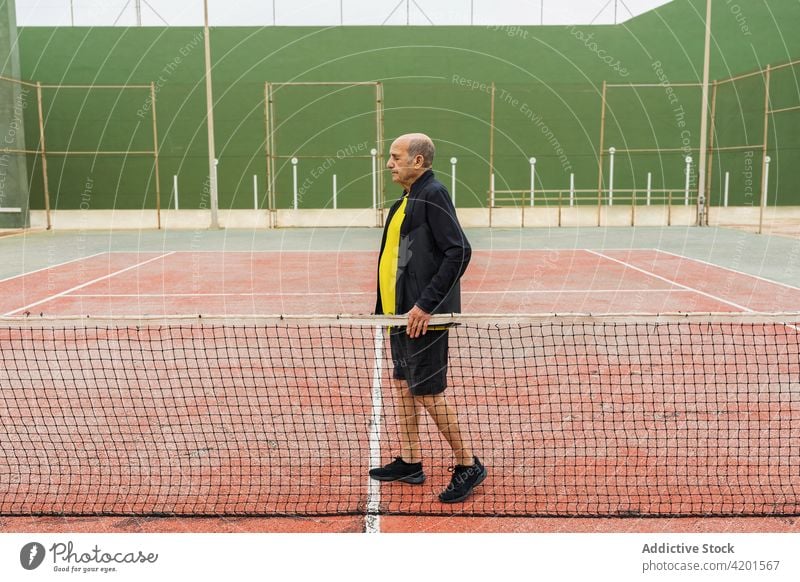 Senior tennis player near net sportsman court ball training activity game match male elderly senior aged shabby weathered athlete workout challenge hobby