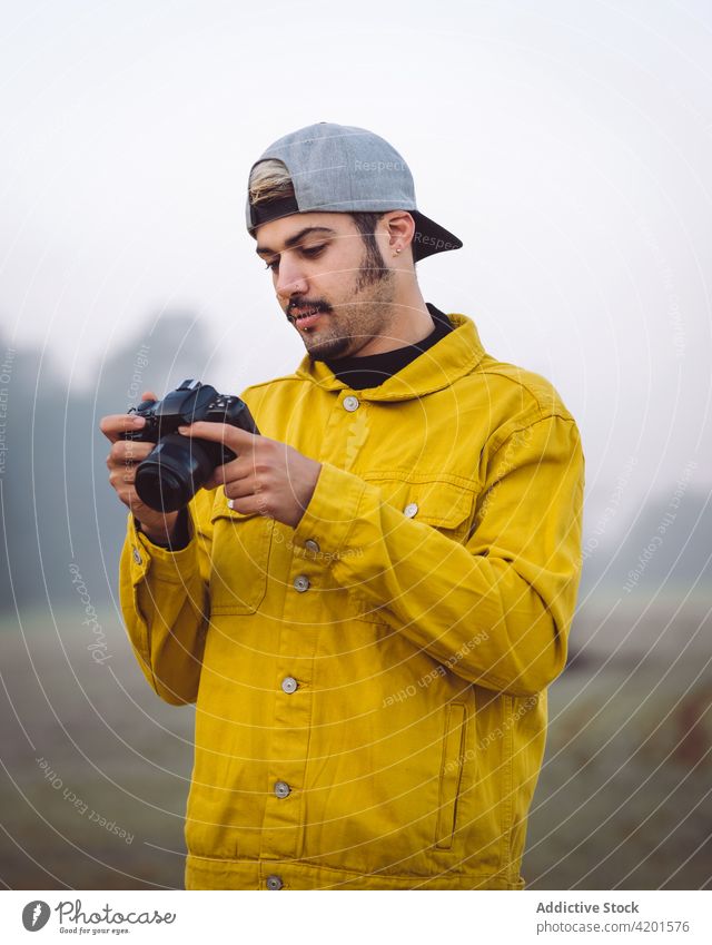 Man taking photo on camera in misty nature man take photo countryside fog photography photographer photo camera meadow denim lifestyle device gadget young