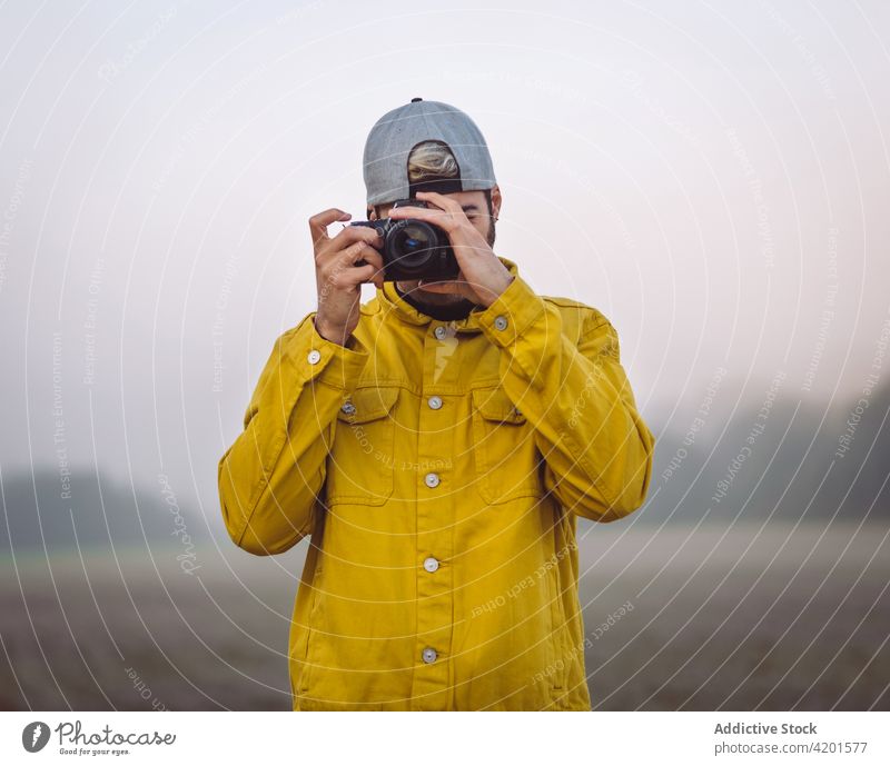 Man taking photo on camera in misty nature man take photo countryside fog photography photographer photo camera meadow denim lifestyle device gadget young