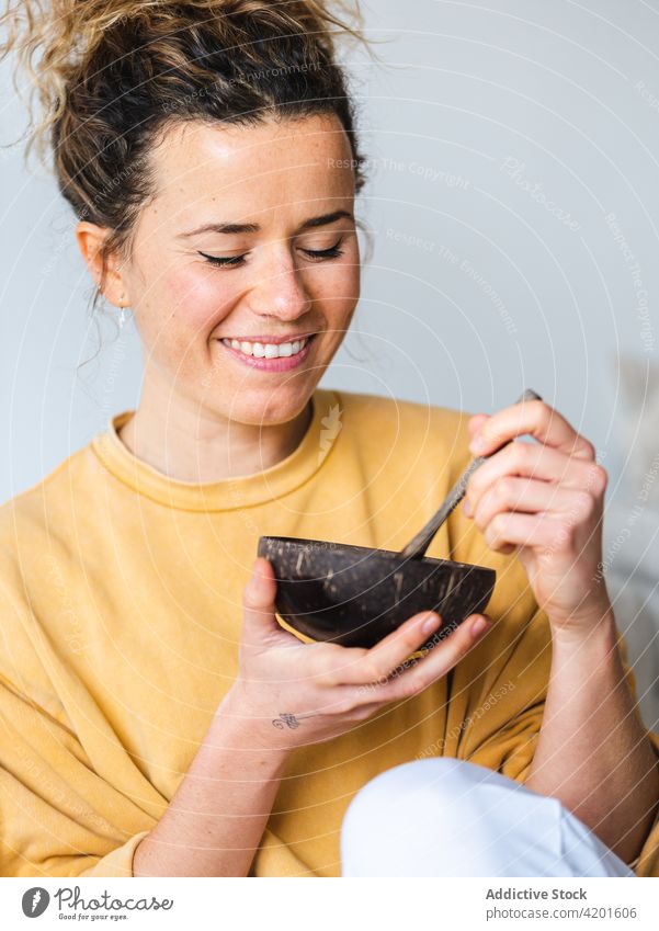 Blonde female with wooden bowl of healthy food at home woman positive apartment smile mango young room cheerful happy eat tasty indoors vertical breakfast yummy