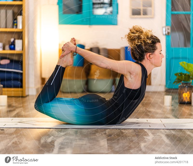Flexible female doing bow pose in yoga studio woman asana concentrate dhanurasana wellness practice wellbeing flexible zen stretch energy harmony vitality
