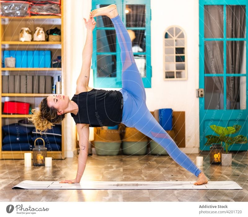 Slim female performing Extended Side Plank pose while practicing yoga at home woman calm tranquil extended side plank asana wellness practice studio flexible