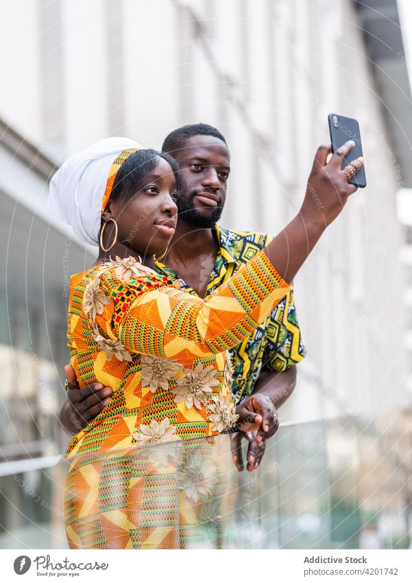 Glad black couple taking selfie on smartphone in city moment memory relationship love content portrait using gadget device smile self portrait ornament