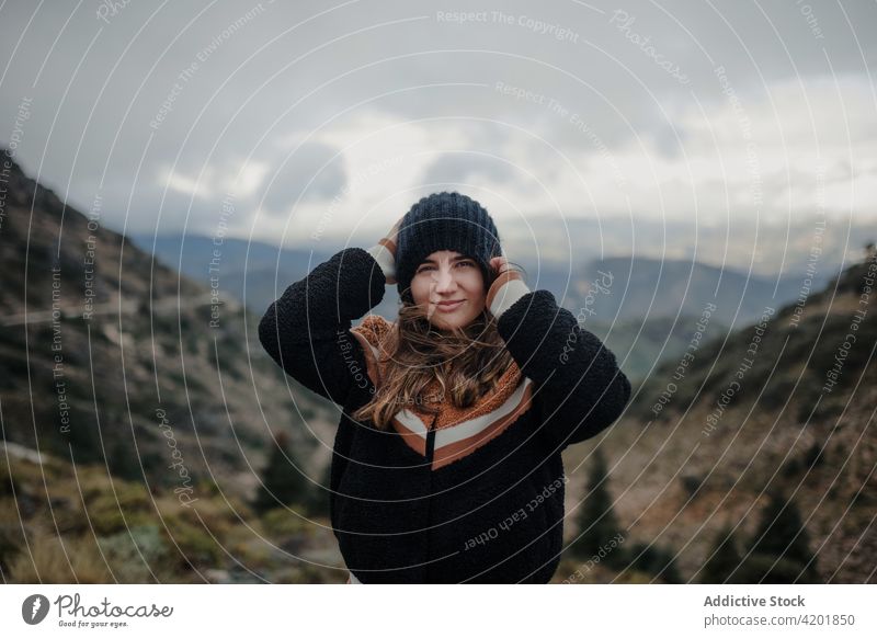 Cheerful woman putting on hat on picturesque highlands put on cloudy gloomy rough cheerful smile nature weather happy young beautiful joy cadiz spain glad