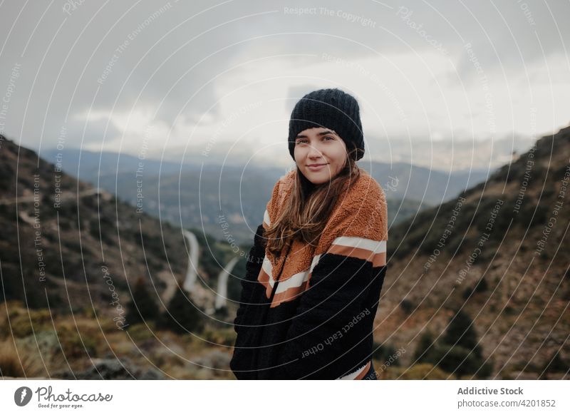 Cheerful woman standing on highlands and looking at camera hat cloudy gloomy rough cheerful smile nature weather happy young beautiful joy cadiz spain glad