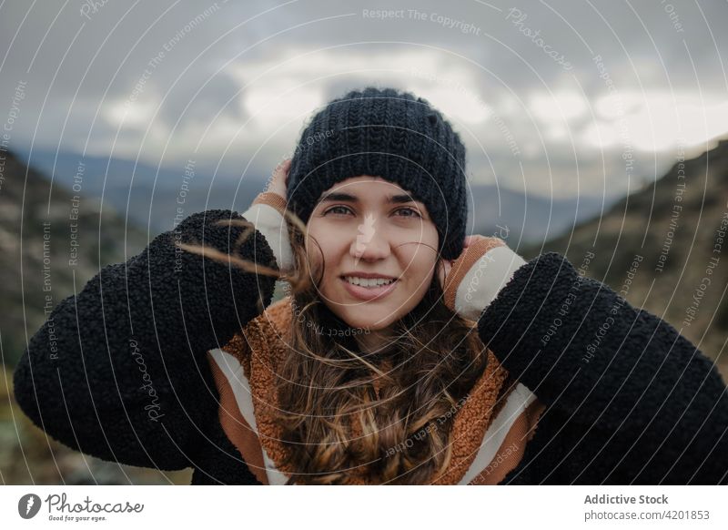 Cheerful woman putting on hat on picturesque highlands put on cloudy gloomy rough cheerful smile nature weather happy young beautiful joy cadiz spain glad