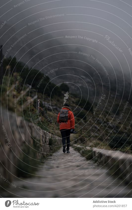 Unrecognizable traveler walking on footpath in misty highlands backpacker pathway fog gloomy warm clothes dull nature countryside hike trekking cadiz spain