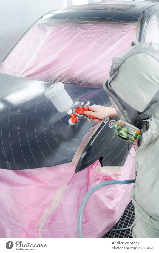 Man in workwear painting car in workshop man gun aerosol spray respirator protect worker automobile mask master suit safe uniform occupation tool professional