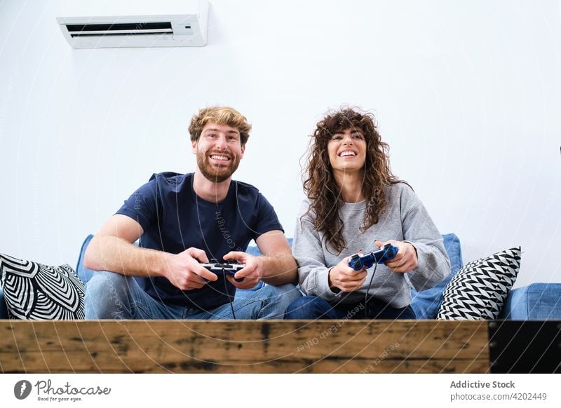 Young couple playing video game at home console room together happy videogame enjoy excited cheerful relationship love fun gadget entertain gamepad relax