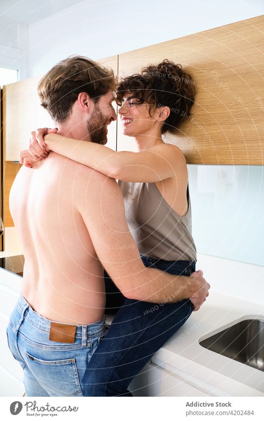 Couple embraced in kitchen on counter couple hug love relationship boyfriend girlfriend romantic young casual light together affection tender shirtless fondness