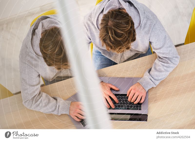 Faceless man working remotely on laptop in room freelance home modern self employed workplace job occupation male using light apartment netbook chair casual
