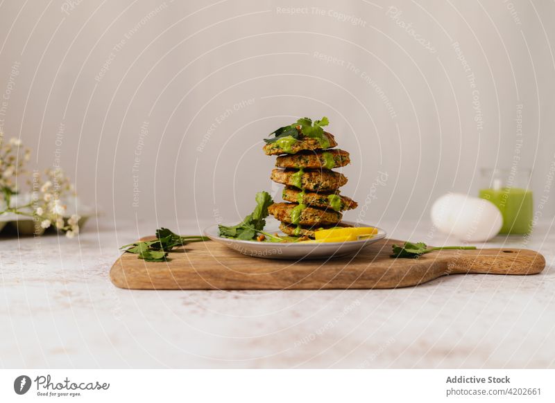 Tasty vegetable fritters stacked on plate on wooden board herbal appetizing vegetarian cuisine serve dish garnish culinary yummy delicious meal fresh tasty