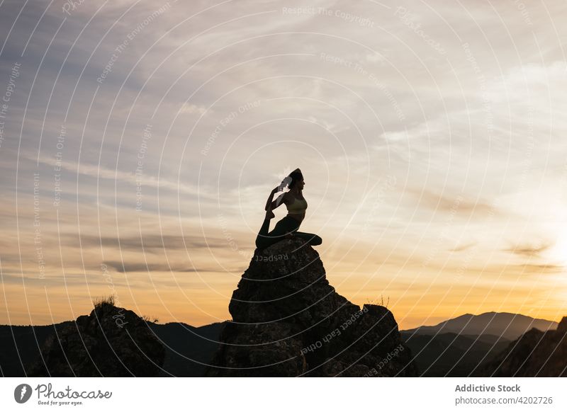 Unrecognizable woman enjoying yoga on rocky formations sundown mountain mermaid asana harmony balance silhouette flexible female eka pada rajakapotasana