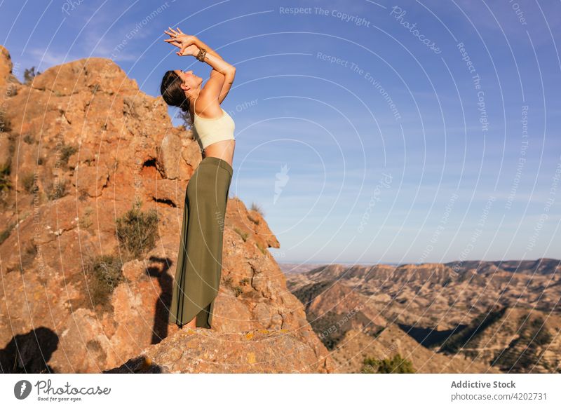 Young woman standing in yoga pose on mountain posture practice healthy highland energy balance female upward hand posture nature cliff freedom exercise stretch