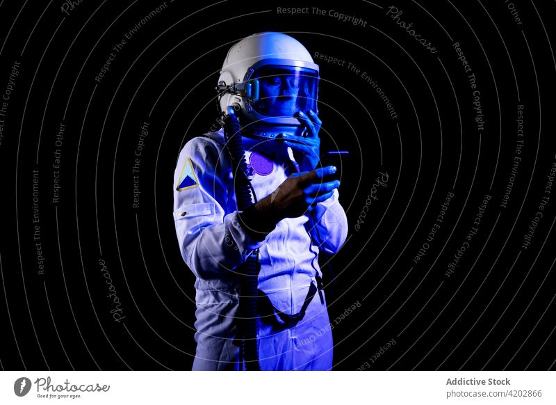 Astronaut in spacesuit using smartphone on black background astronaut man browsing armor astronomy gadget professional serious cosmonaut protective spaceman