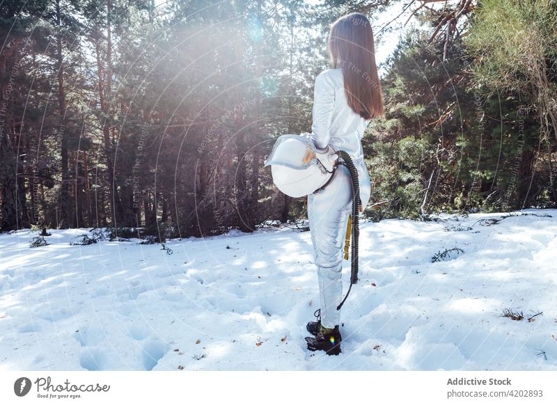 Anonymous female astronaut standing in snowy forest woman cosmonaut spacesuit calm winter astronomy helmet explorer professional serious protective armor