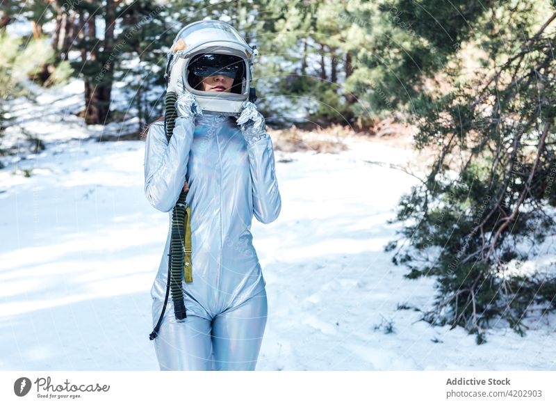 Anonymous determined female in space helmet standing in snowy forest astronaut spacesuit serious woman spacewoman cosmonaut winter astronomy beauty explorer