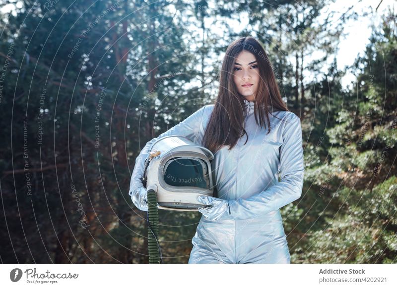 Attractive female astronaut standing in snowy forest woman cosmonaut spacesuit calm winter astronomy helmet explorer unemotional professional serious protective