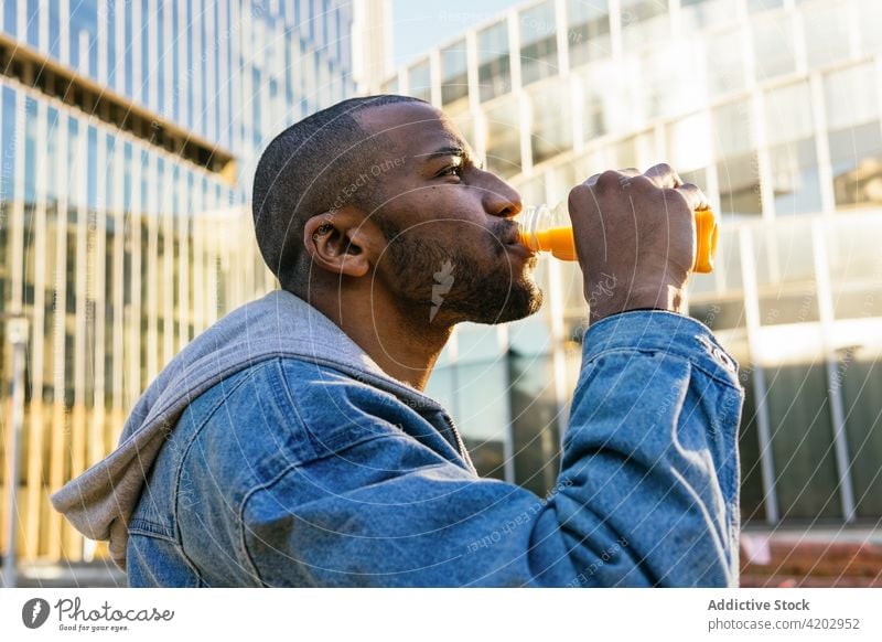 Black man drinking delicious beverage on city street juice refreshment bottle enjoy contemplate masculine portrait african american town healthy drink bright