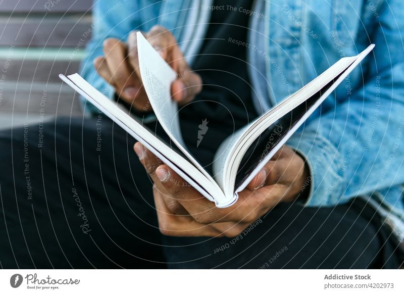 Anonymous black man with diary on city street journal attentive read masculine brutal book macho town portrait tropical exotic watching denim jacket cloth