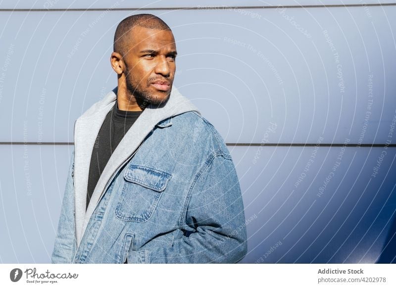 Masculine black man in hoodie near tiled wall hand in pocket style casual masculine cool macho brutal portrait town city modern street contemplate emotionless