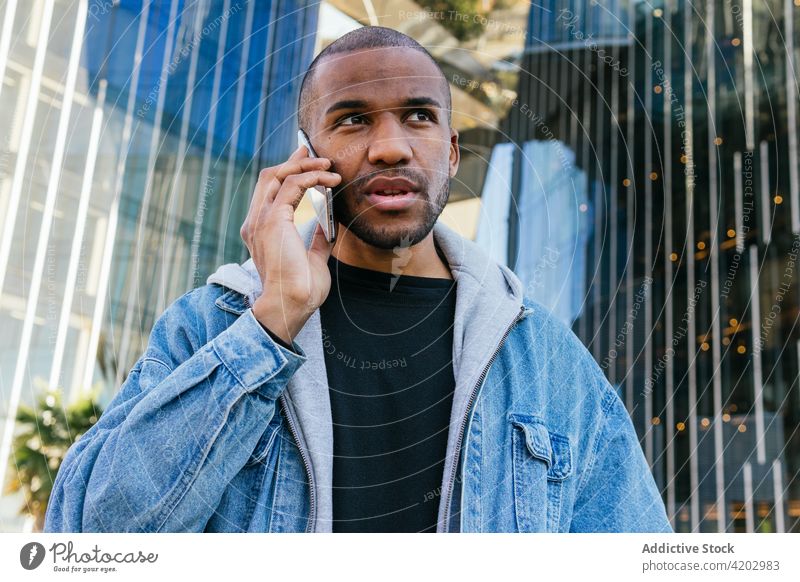 Masculine black man speaking on smartphone on city street masculine brutal macho phone call portrait using gadget device cellphone talk conversation modern