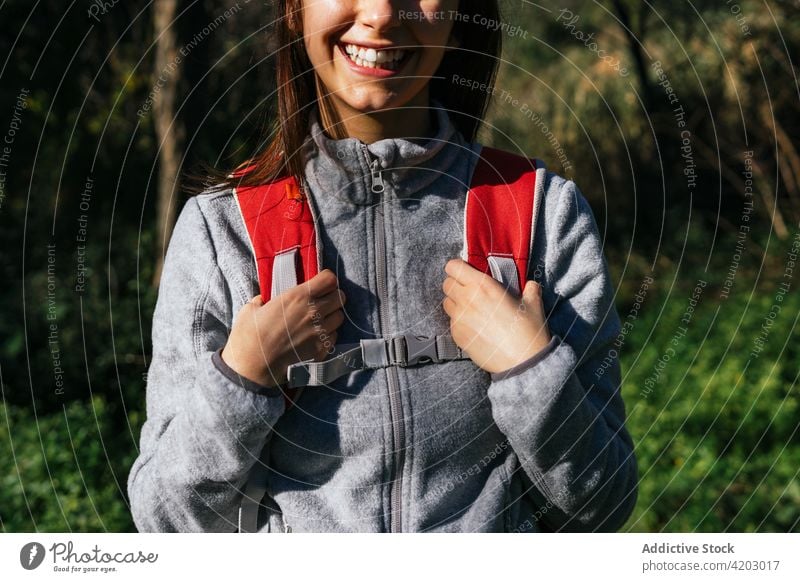 Anonymous cheerful woman with backpack hiking in forest hiker happy sunlight active nature smile young female lifestyle activity recreation wellness healthy