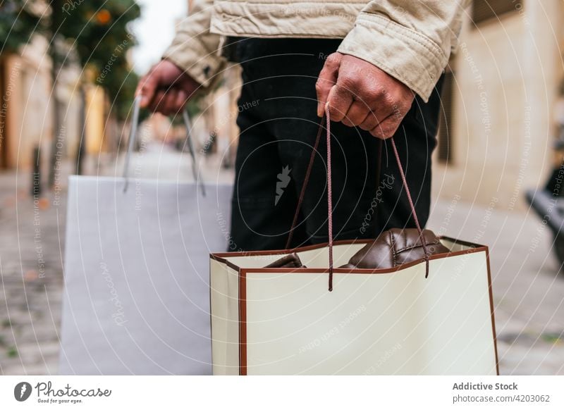 Male hopper with gift bags walking on city street shopper shopping bag masculine style man urban lifestyle present surprise romantic modern stylish town
