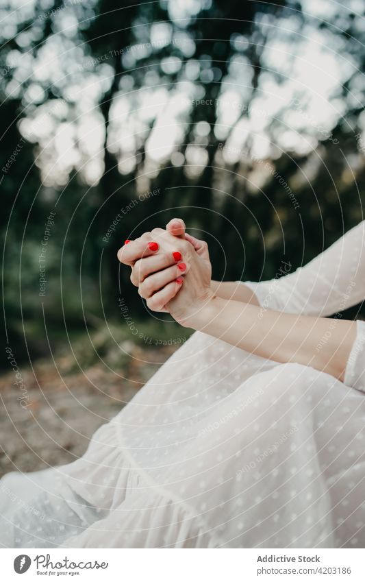 Crop woman with clasped hands in nature hands clasped manicure white dress gown rural countryside park tree female environment forest red lady serene woods