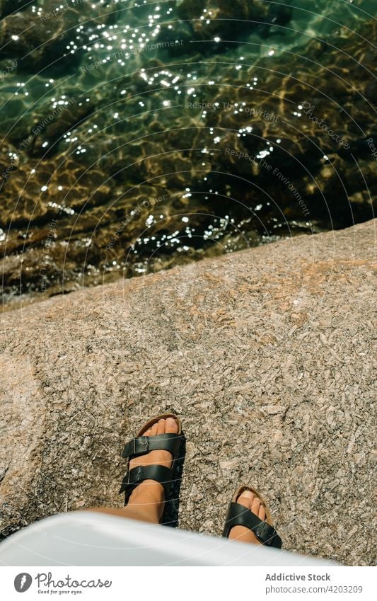 Close-up of women's sandals on some rocks and the sea below feet close-up beach summer background foot stone close up footwear girl shoe travel white outdoor