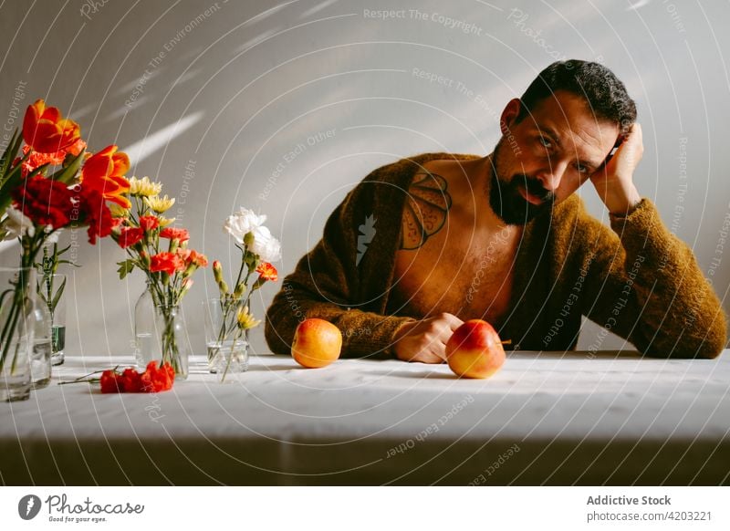 Thoughtful man with fresh flowers in glass placed on table tulip ripe apple thoughtful bouquet blossom male ponder carnation beard stem plant vitamin delicious