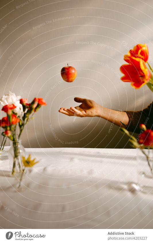 Person throwing apple in studio with flowers person ripe levitate fly fruit tulip carnation bloom toss blossom food bouquet floral delicious natural vitamin