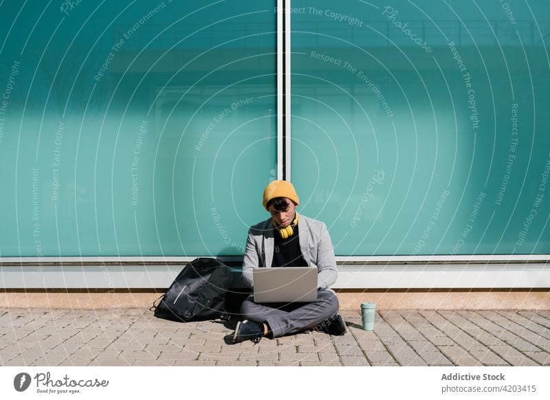 Man typing on laptop in city street man student campus homework project hipster university study male education takeaway drink gadget using browsing device