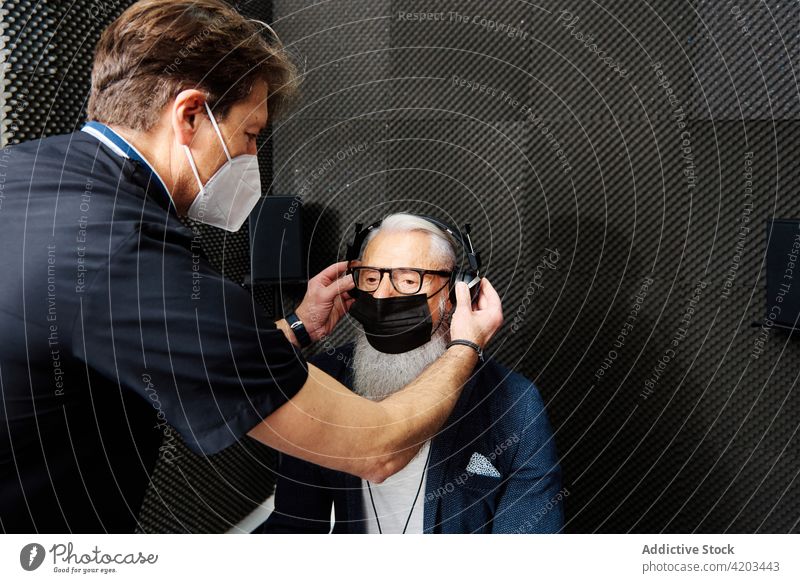 Doctor preparing elderly patient for audiological examination hear check audiology test doctor prepare diagnostic senior examine male sound adjust headphones