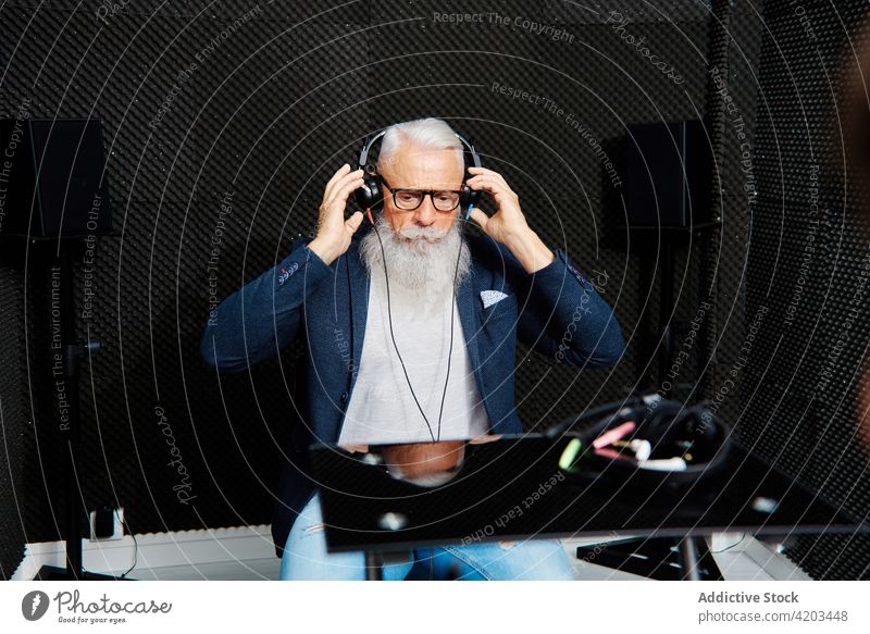 Senior man in headphones during audiology test check hear sound proof diagnostic senior male examine elderly equipment foam soft wall instrument modern