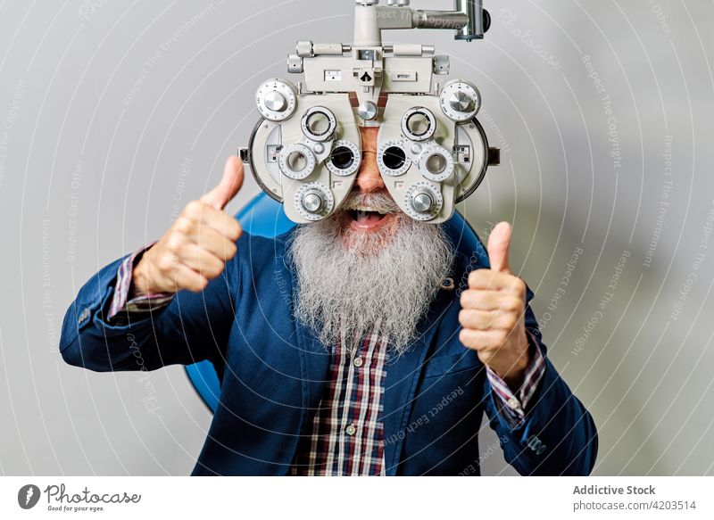Senior male with phoropter during eye examination optometrist eyesight diagnostic optician ophthalmology optometry examine patient senior doctor vision check
