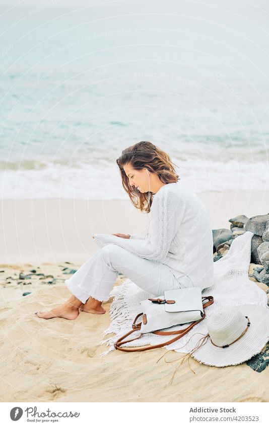 Carefree woman listening to music at seaside tranquil harmony song calm serene beach female coast shore earphones device gadget ocean peaceful idyllic nature