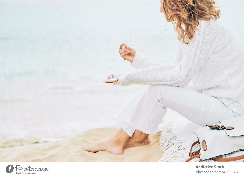Carefree woman listening to music at seaside tranquil harmony song calm serene beach female coast shore earphones device gadget ocean peaceful nature sound sand