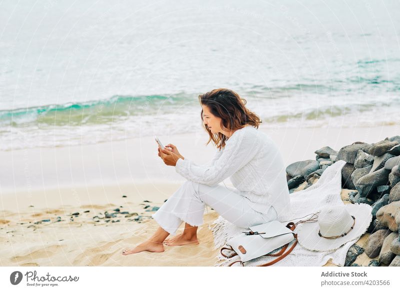 Carefree woman using mobile at seaside listen music tranquil harmony song calm serene beach female coast shore earphones device gadget ocean peaceful nature