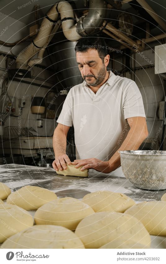 Ethnic baker preparing bread at table in kitchen man prepare form dough professional natural bakery ethnic bowl flour attentive uncooked product raw work focus